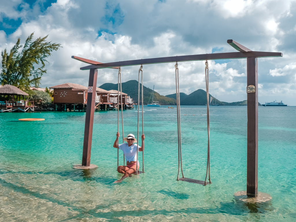 Woman on the beach swinging on a swing watching the ocean while on vacation in St. Lucia. She seems to be saying 'it is safe to travel to the Caribbean'.