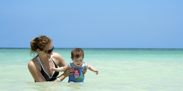 A woman and her son safely playing in the shallow beach waters