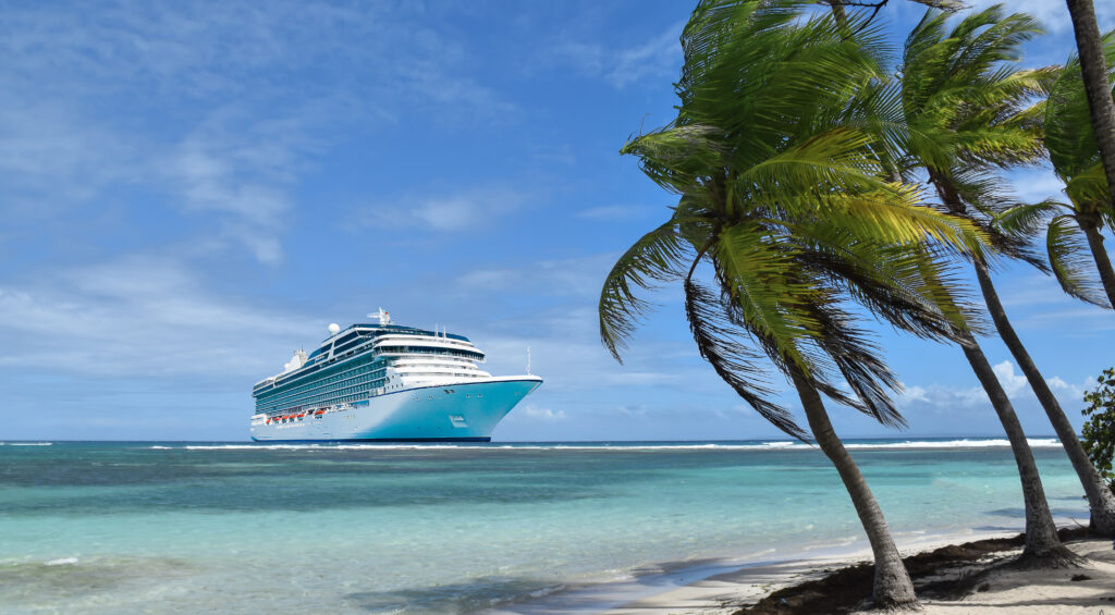 Tropical beach with palm trees and luxury cruise ship on crystal clear Caribbean Sea. Summer travel concept.