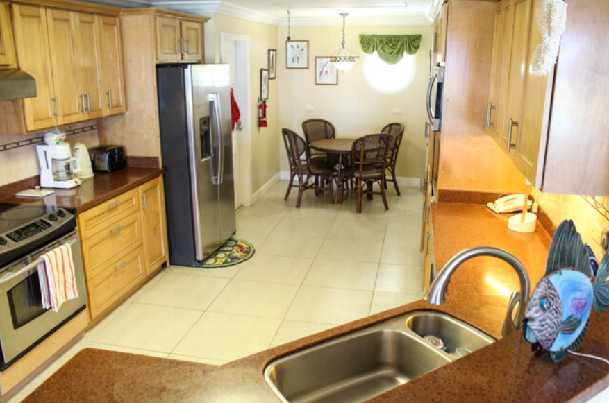 A full kitchen with fridge, stove, coffee maker, toaster, can opener, table and chairs